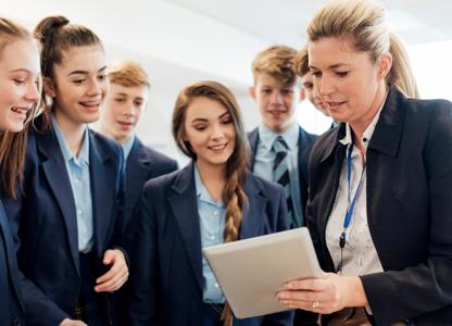 Group of students gathered around another person holding a tablet during a lab activity